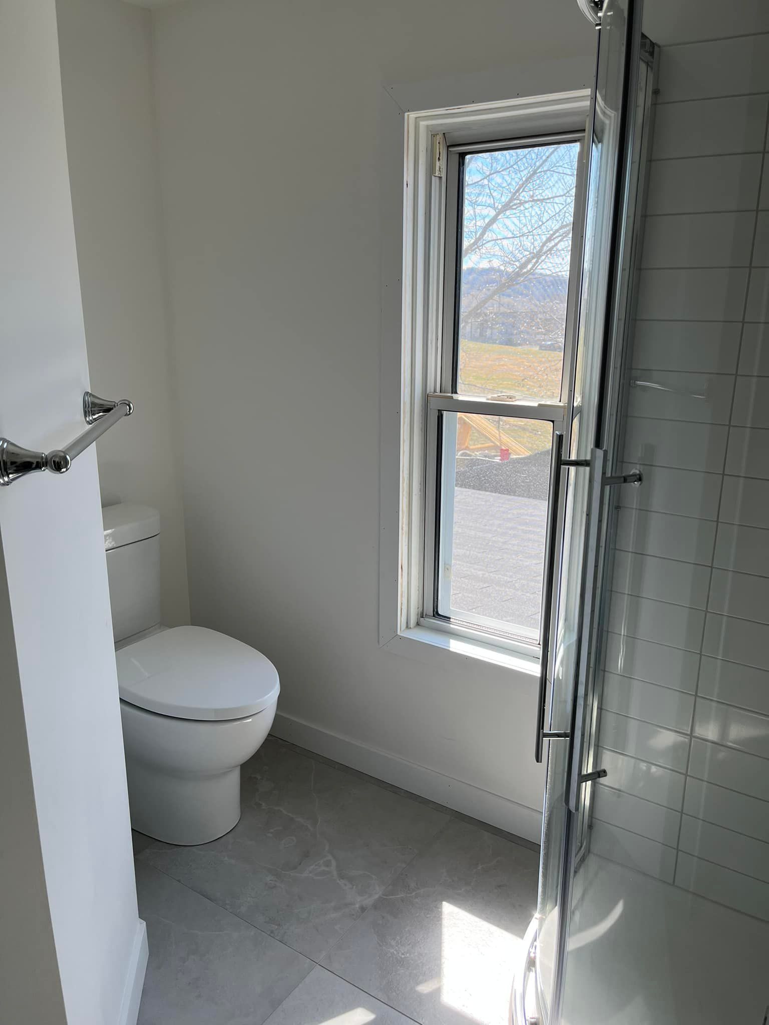 Une salle de bain avec WC, douche et fenêtre.