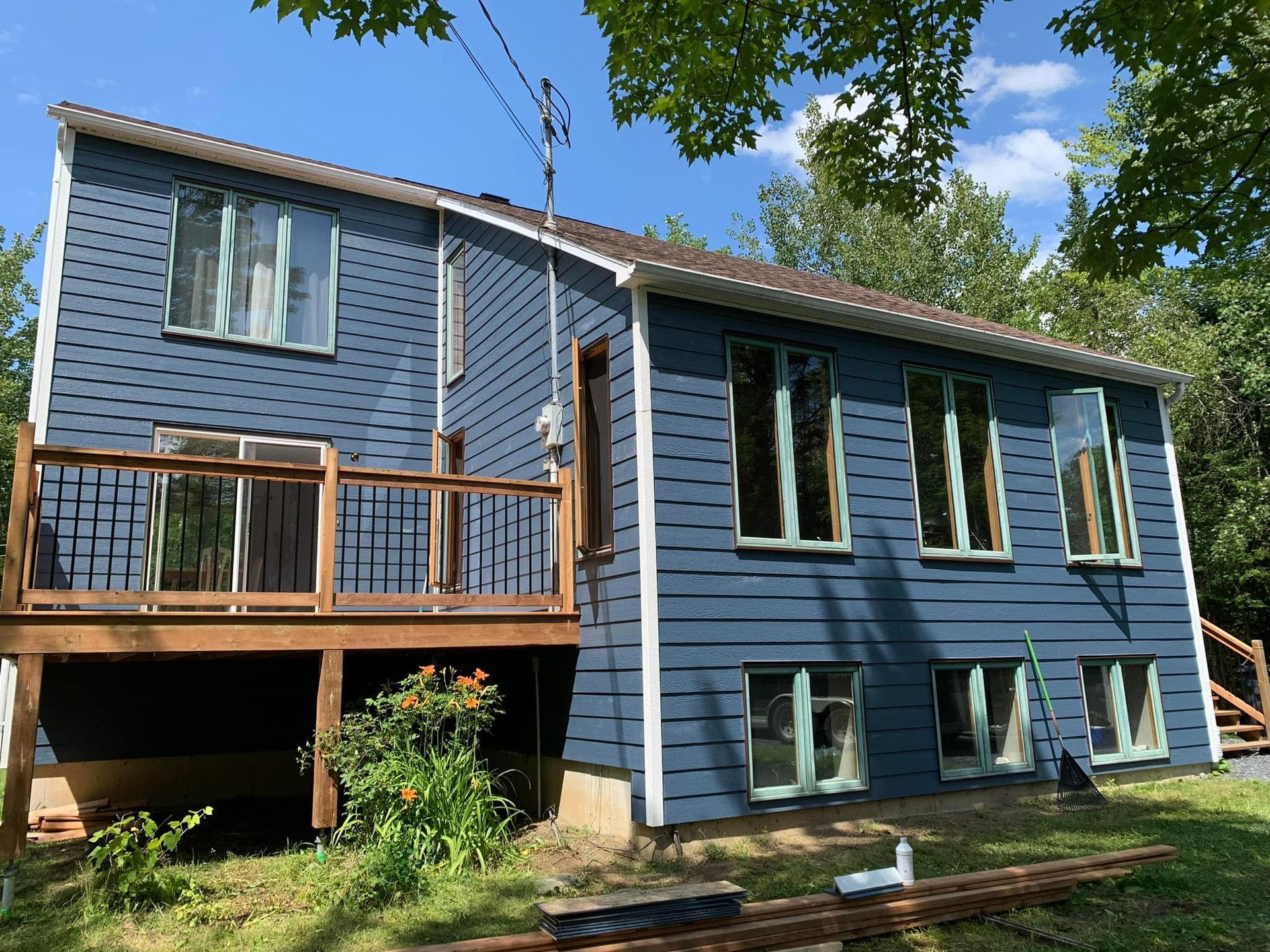 Une maison bleue avec une terrasse et beaucoup de fenêtres