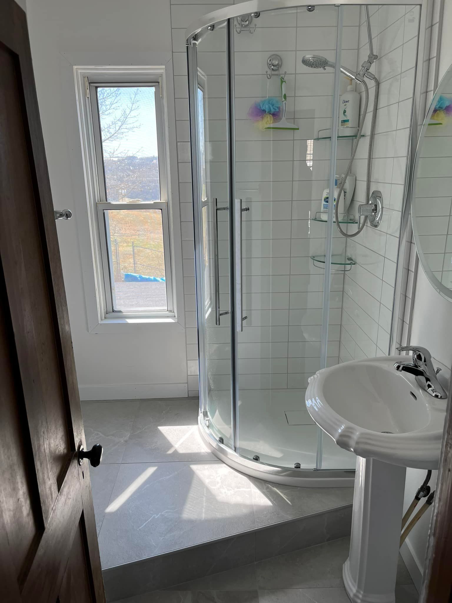Une salle de bain avec lavabo, douche et fenêtre.