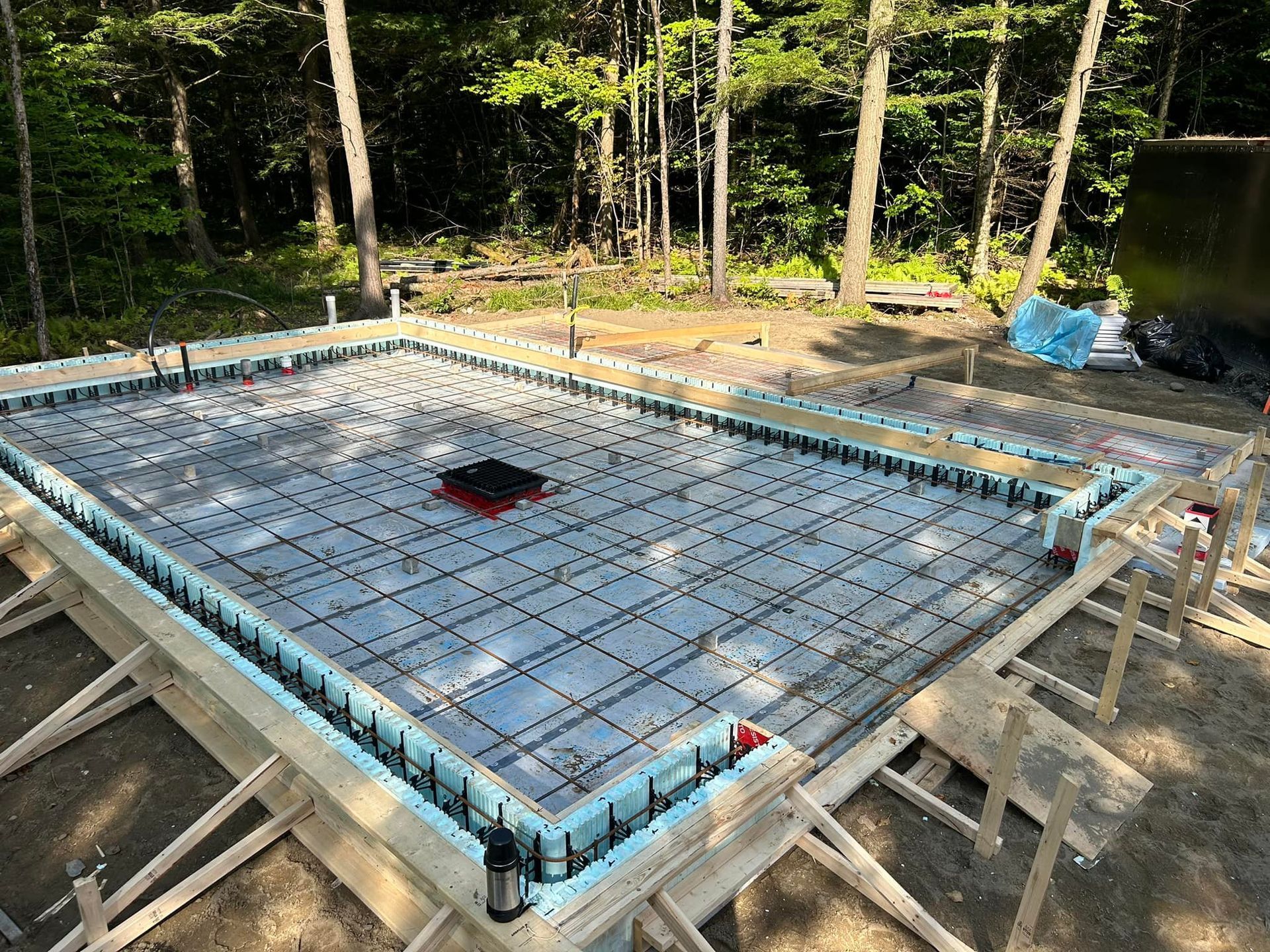 Une base en béton pour une maison est en cours de construction dans les bois.