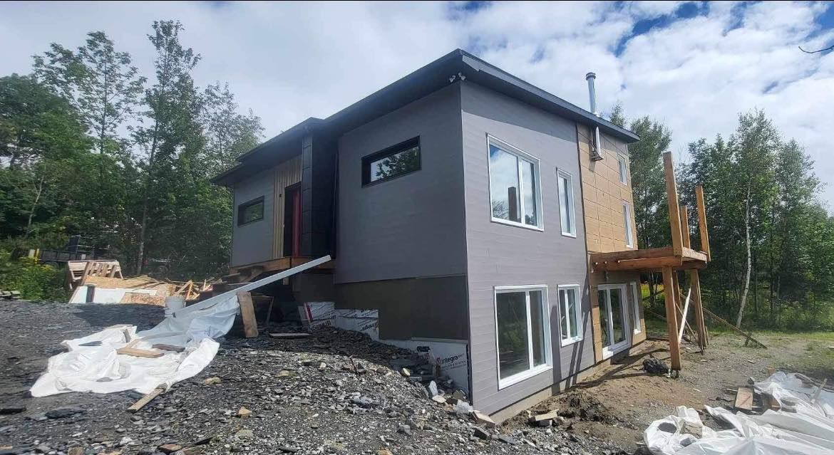 Une grande maison est en construction au sommet d'une colline rocheuse.