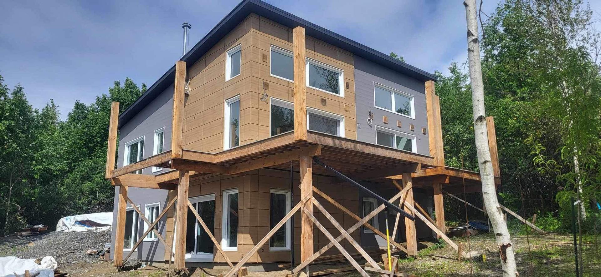 Une grande maison est en construction sur pilotis au milieu d'une forêt.