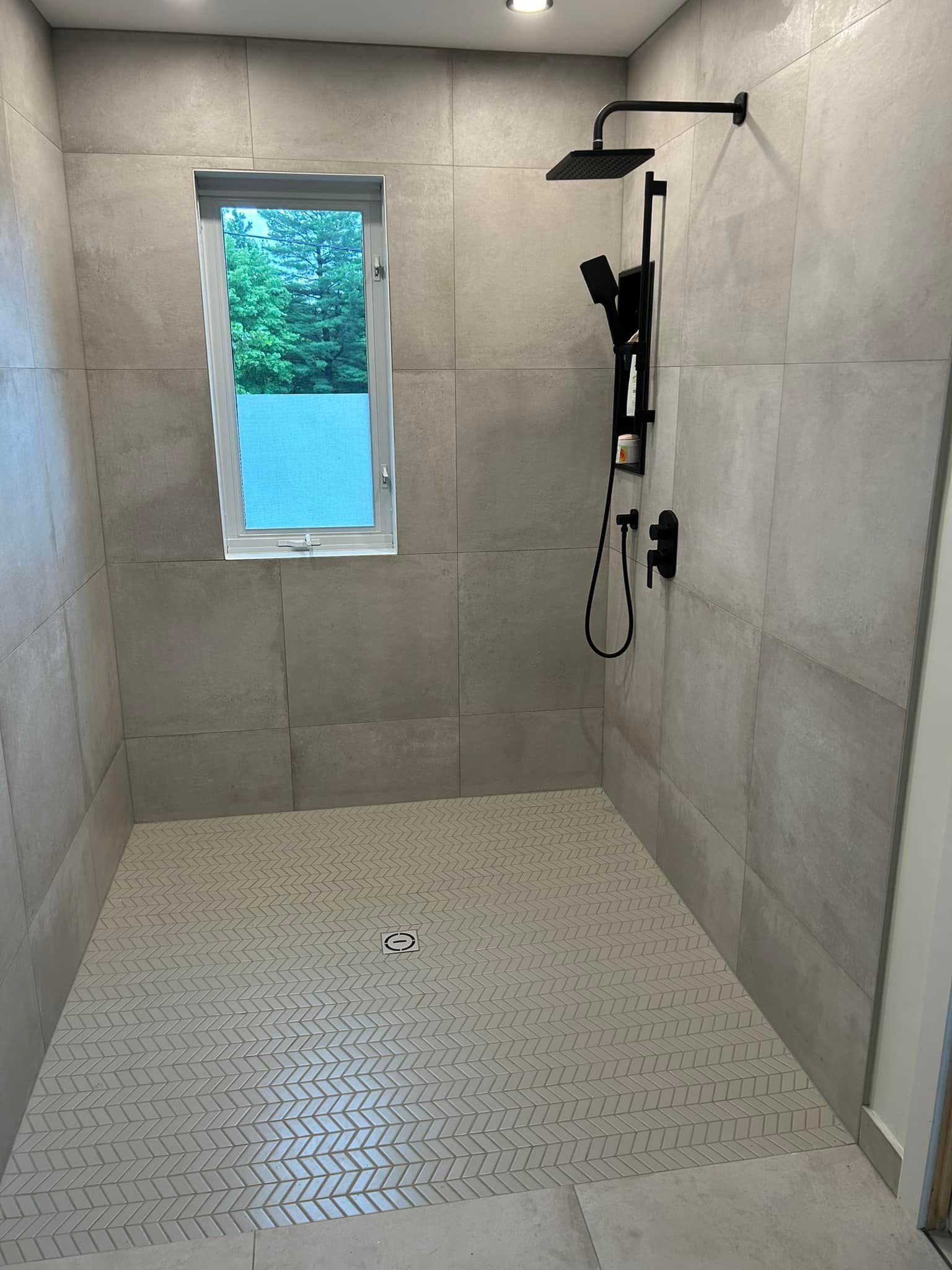 Une salle de bain avec douche à l'italienne et fenêtre.