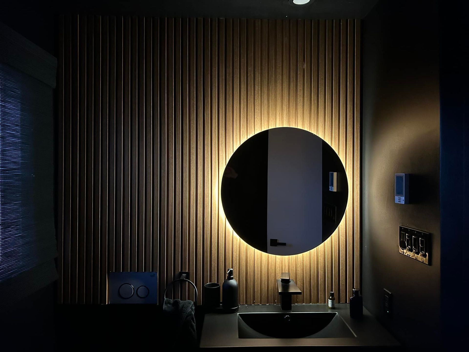 Une salle de bain avec un miroir rond et un lavabo.