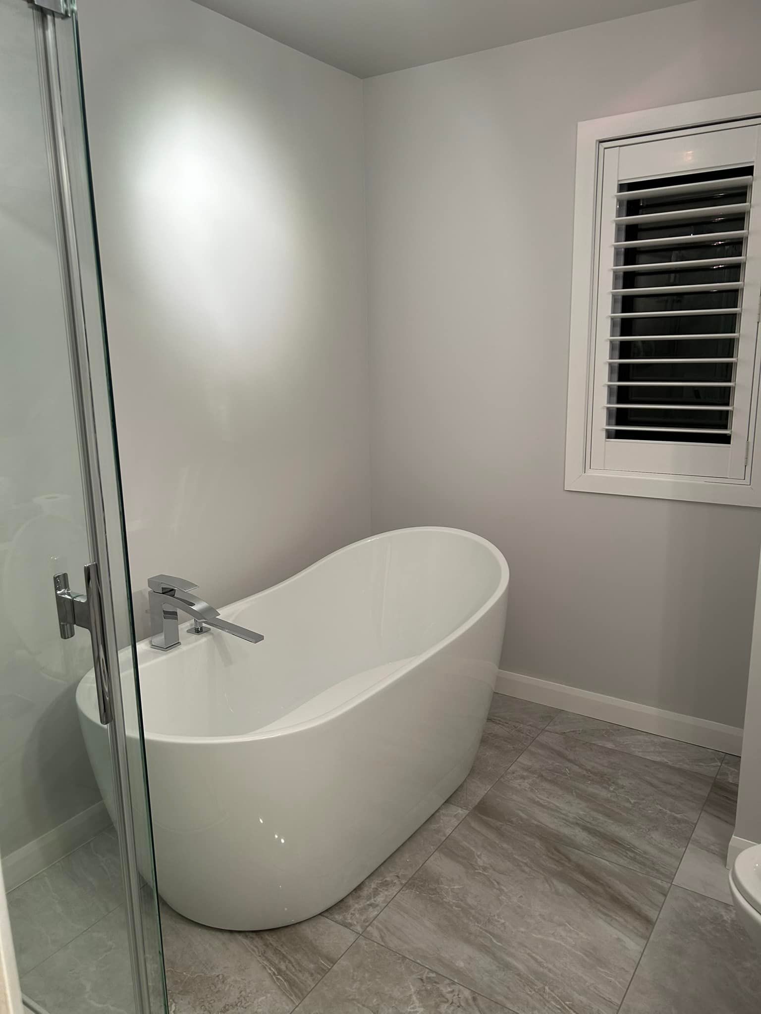 Une salle de bain avec baignoire, douche, WC et fenêtre.