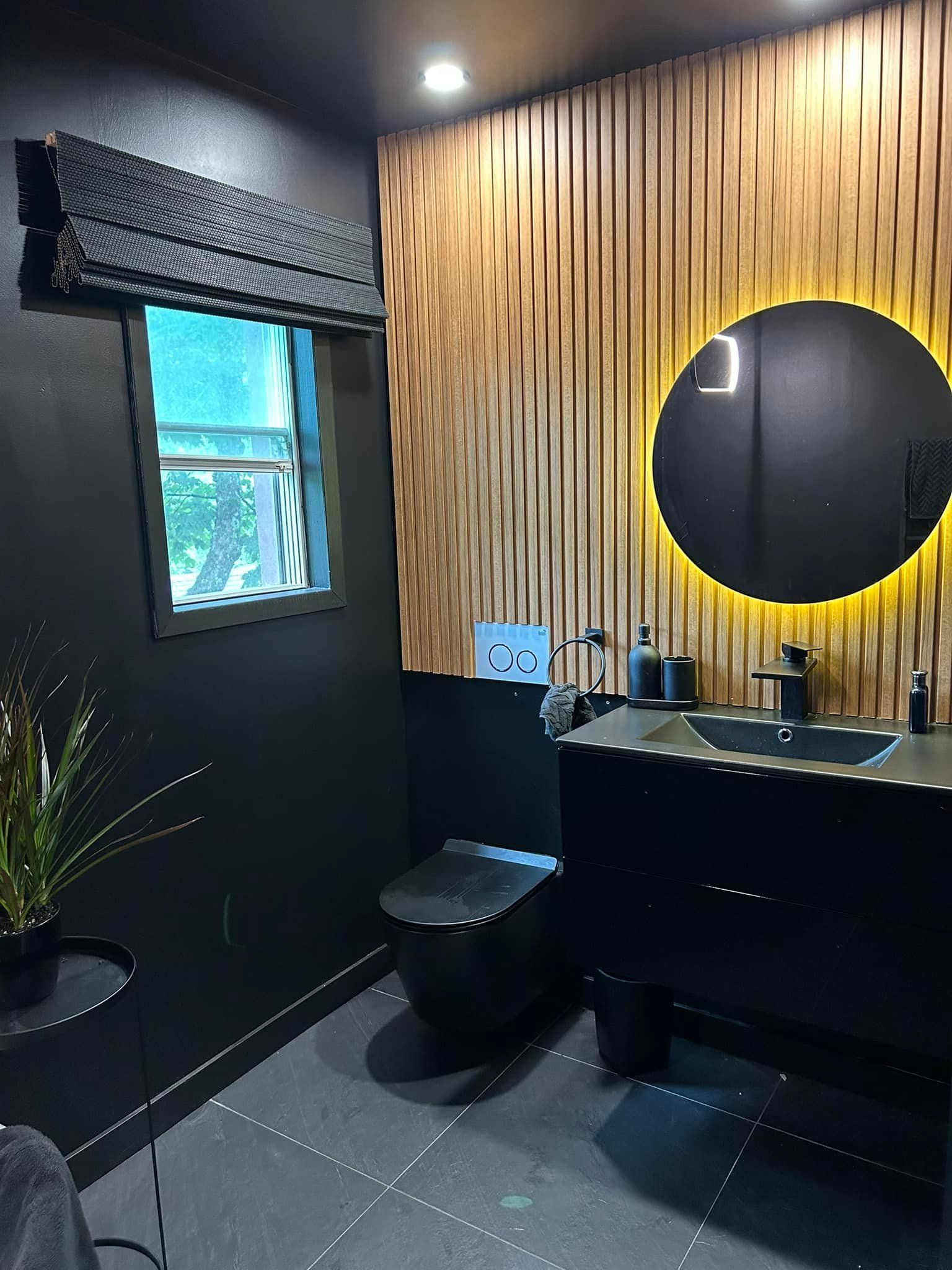 Une salle de bain avec WC, lavabo, miroir et fenêtre.