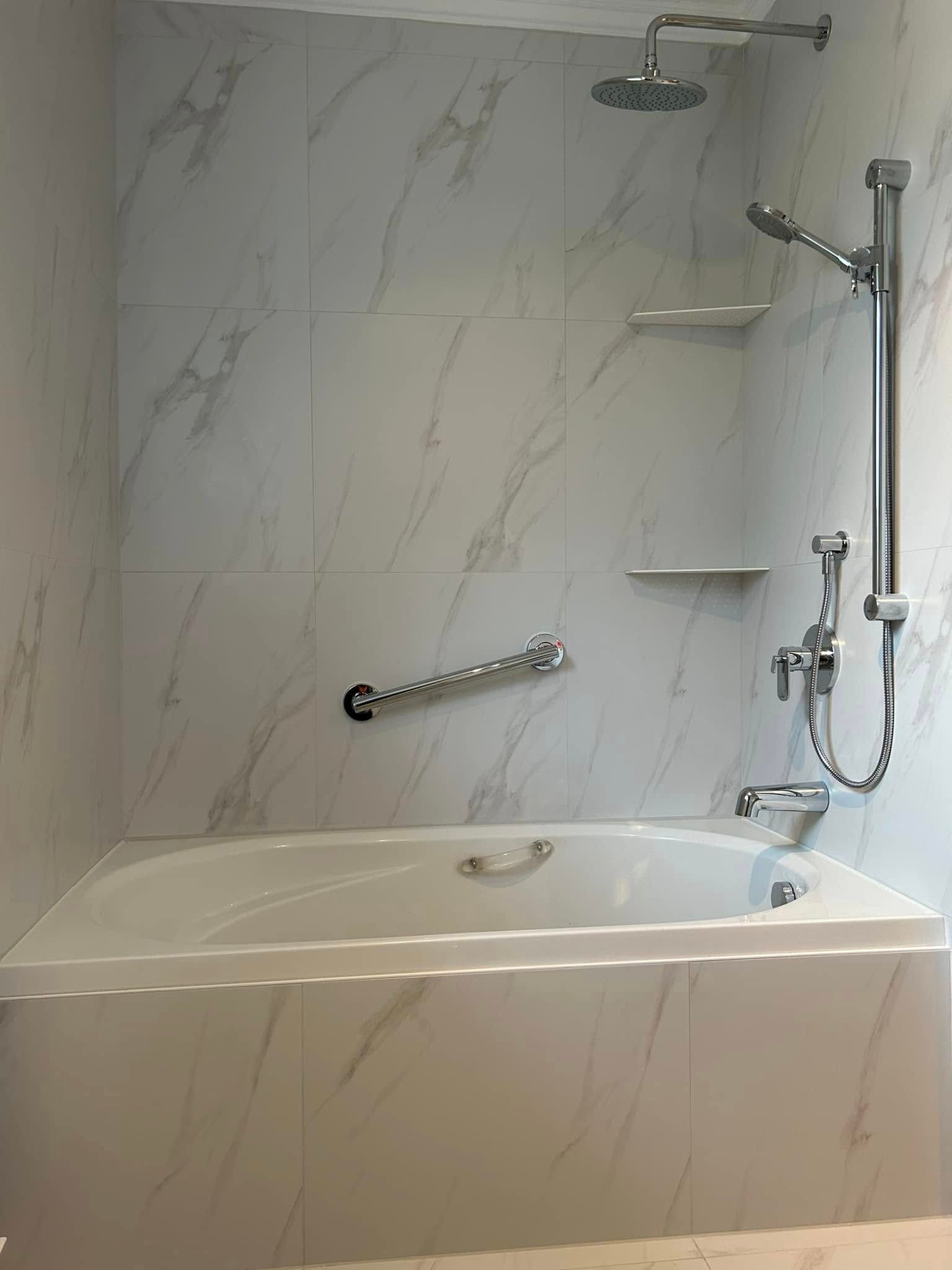 Il y a une baignoire dans la douche avec un pommeau de douche.