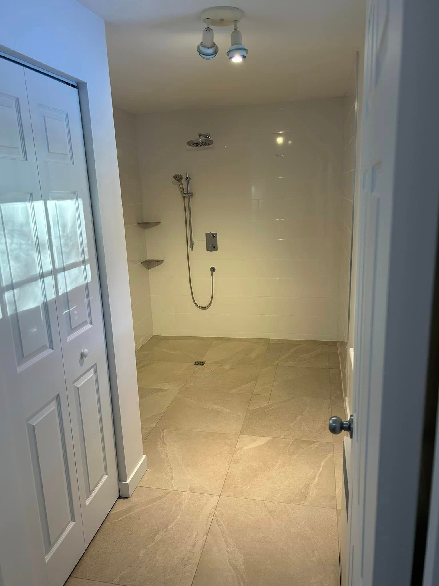 Une salle de bain avec une douche à l'italienne et une porte y donnant accès.