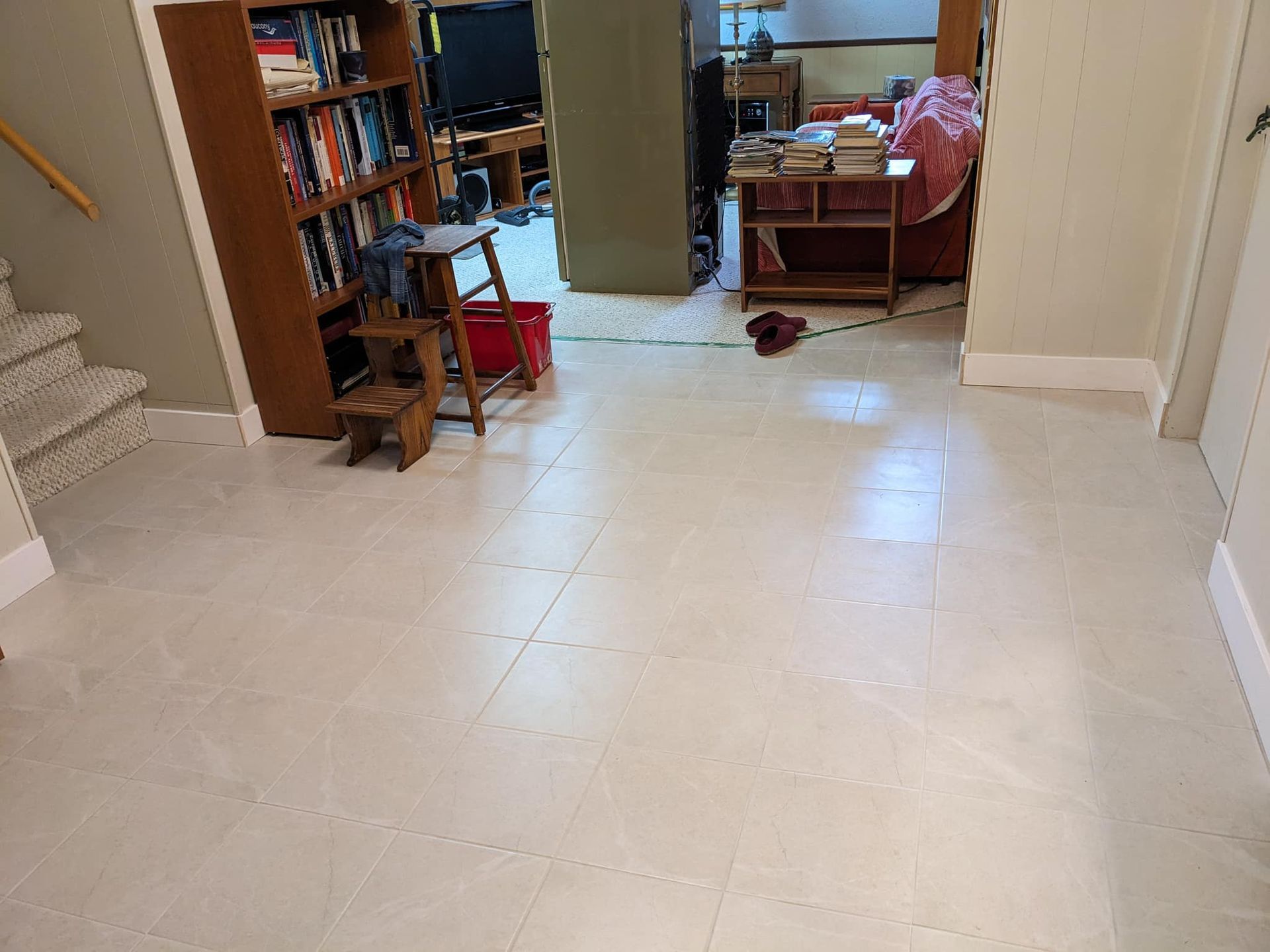 Un salon avec du carrelage blanc et une bibliothèque remplie de livres.