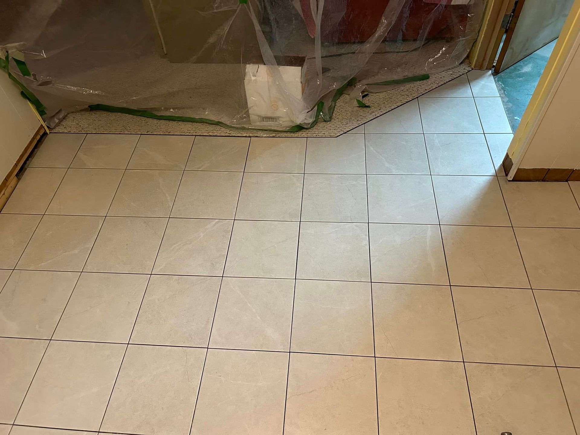 Un sol carrelé dans une pièce recouvert d'une feuille de plastique