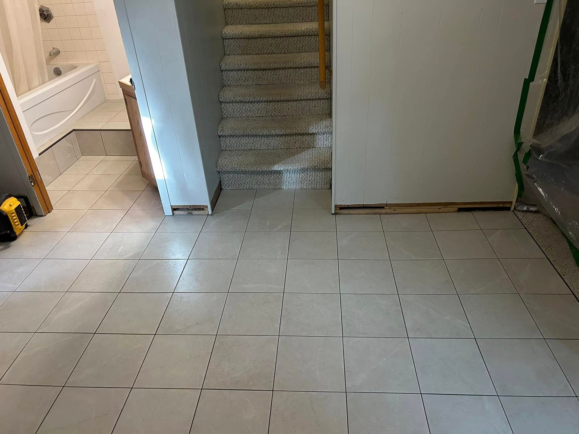 Un sol carrelé dans une salle de bain avec escalier et baignoire.