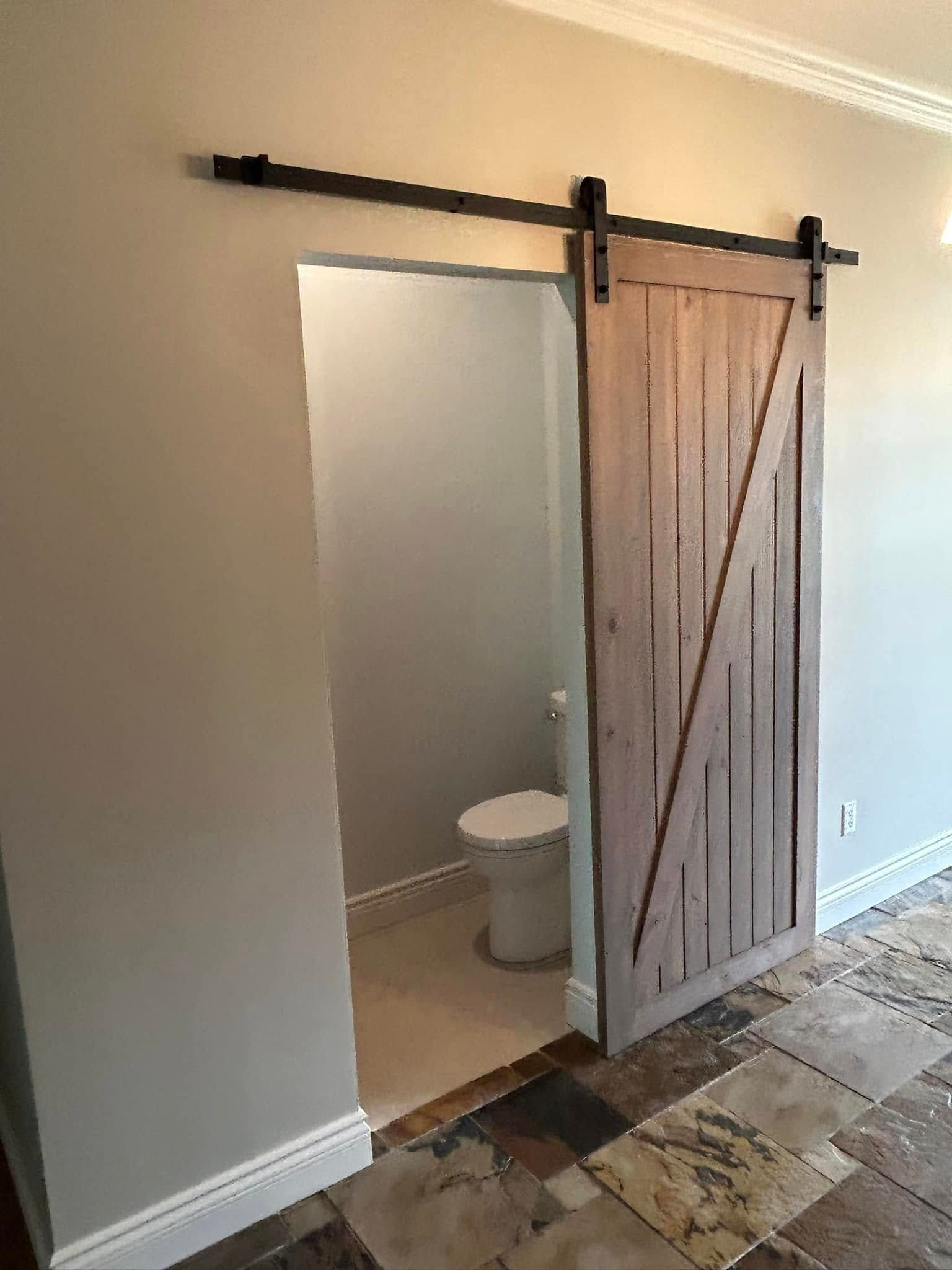 Une salle de bain avec une porte de grange coulissante et un WC.