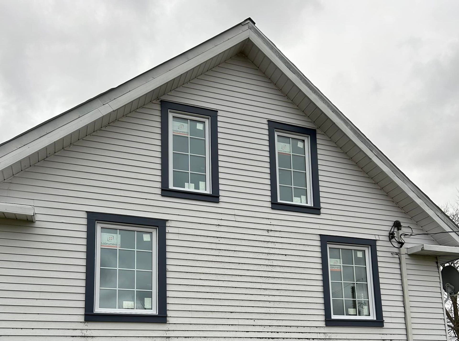 Une maison blanche avec des garnitures noires et trois fenêtres