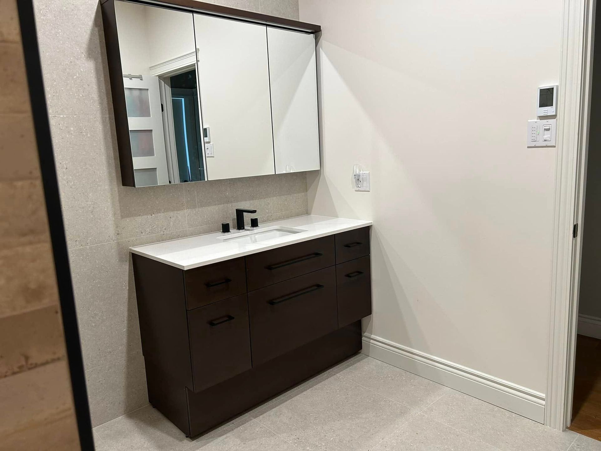 Une salle de bain avec lavabo, miroir et thermostat.