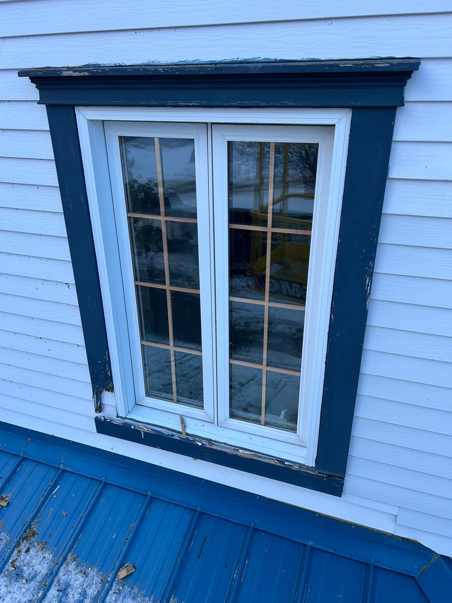 Une fenêtre sur le côté d'une maison avec un toit bleu
