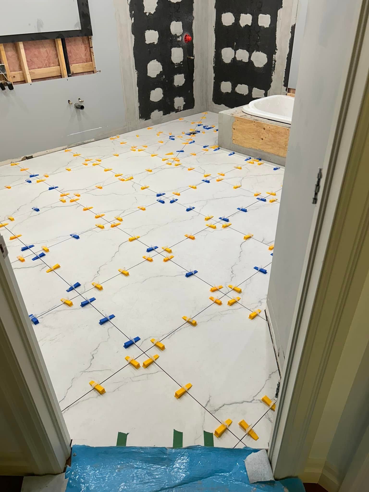 Une salle de bain en construction avec du carrelage au sol et une baignoire.