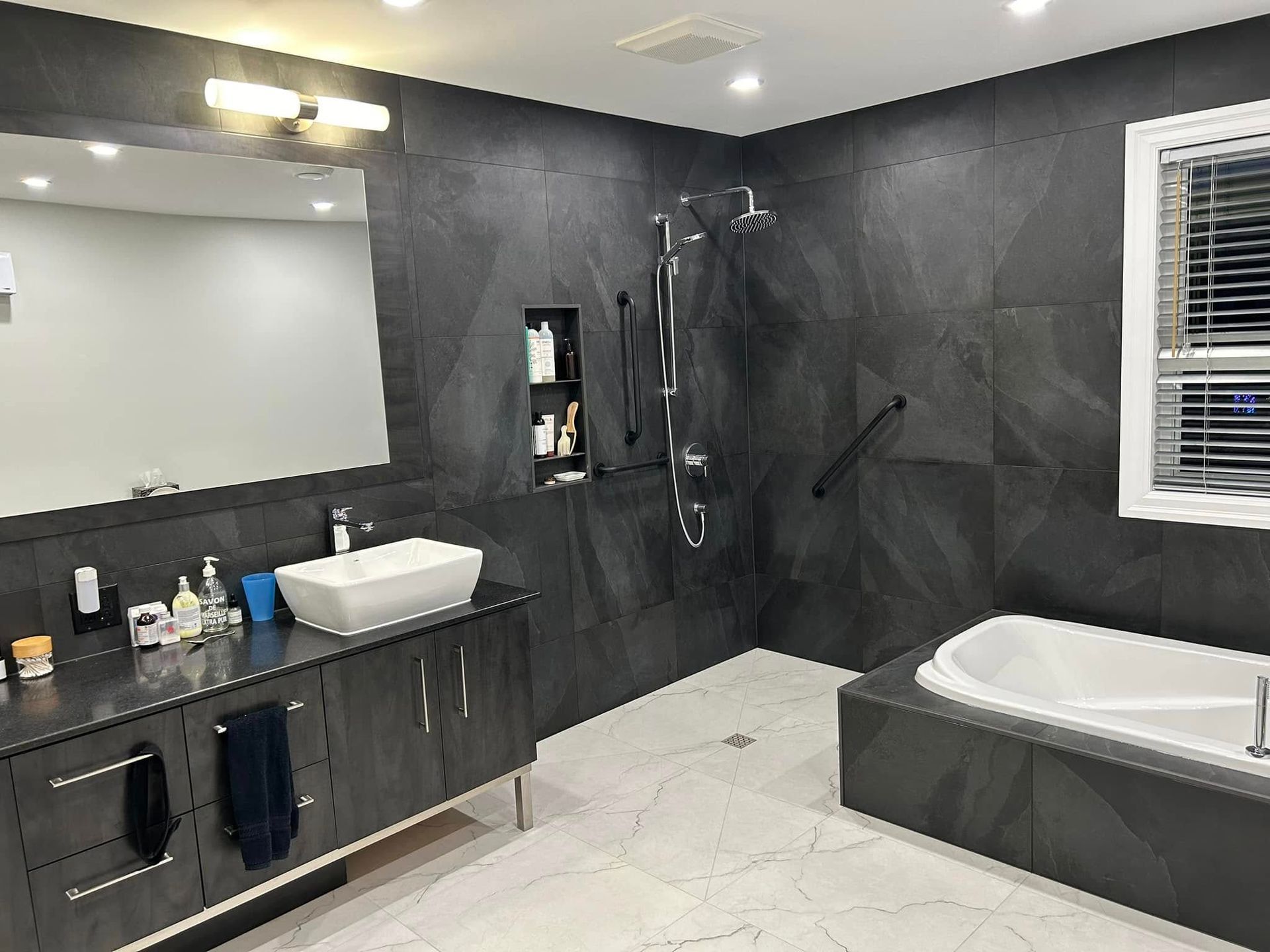 Une salle de bain avec baignoire, lavabo, miroir et douche.