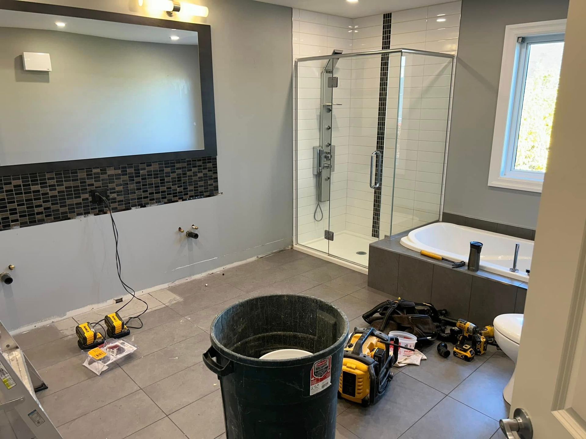 Une salle de bain en construction avec une poubelle au milieu de la pièce.