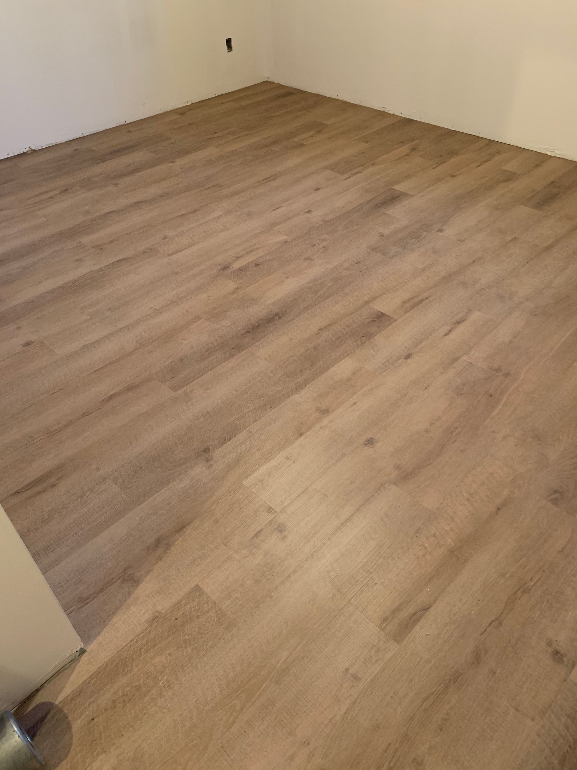 Une pièce avec un plancher en bois et des murs blancs.