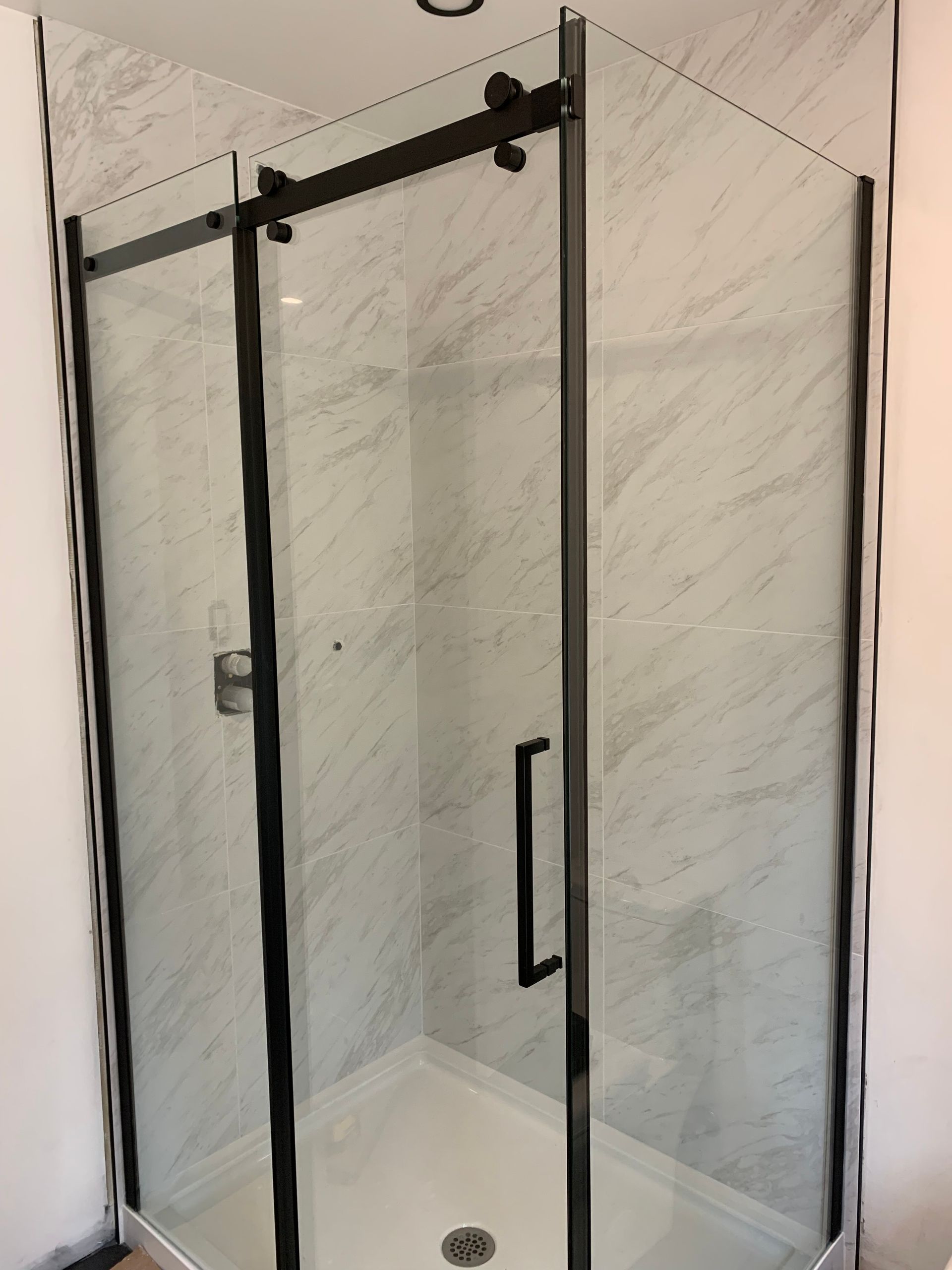Une cabine de douche avec une porte coulissante en verre dans une salle de bain.