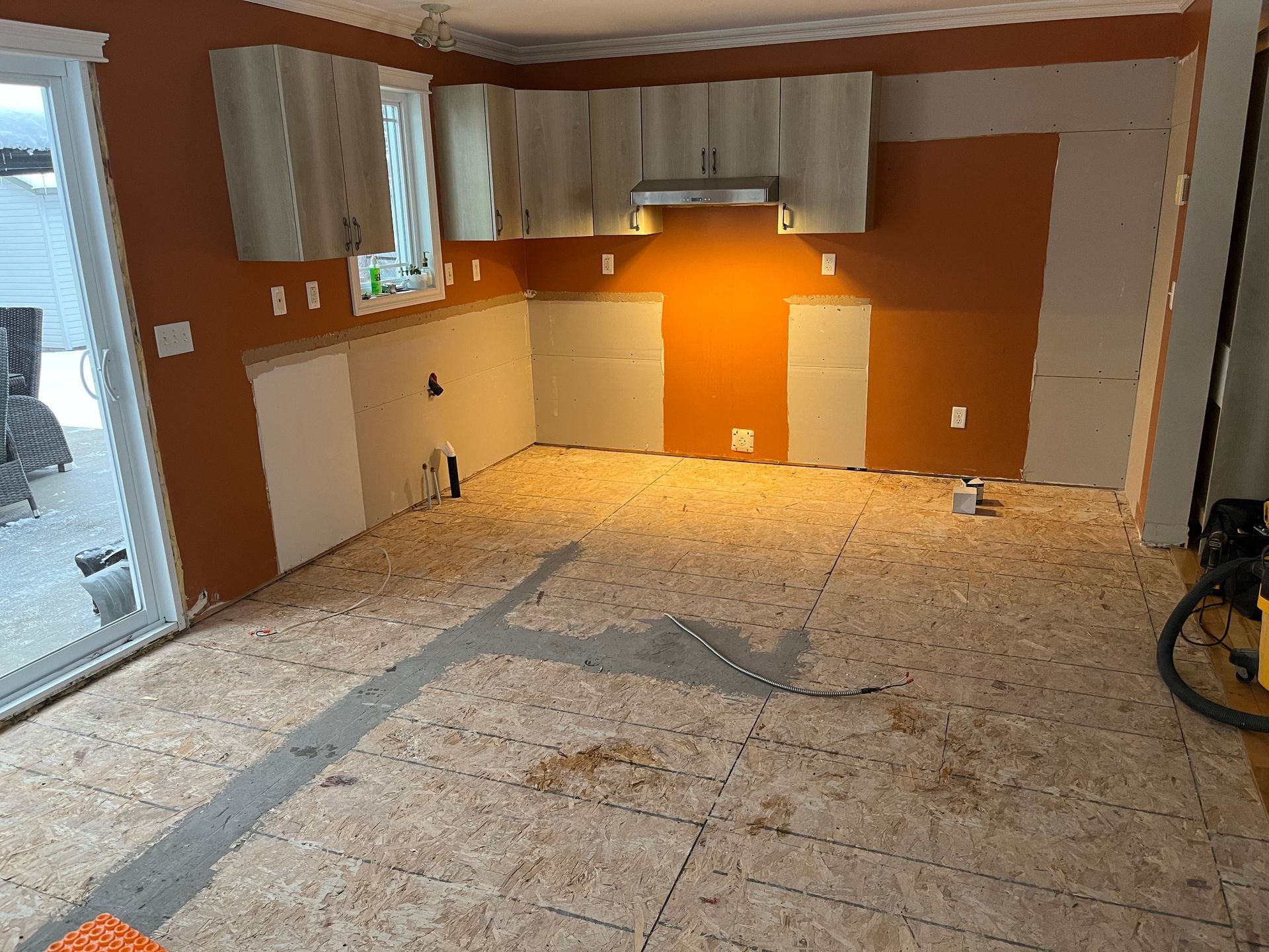 Une cuisine est en cours de rénovation et le sol est recouvert de contreplaqué.