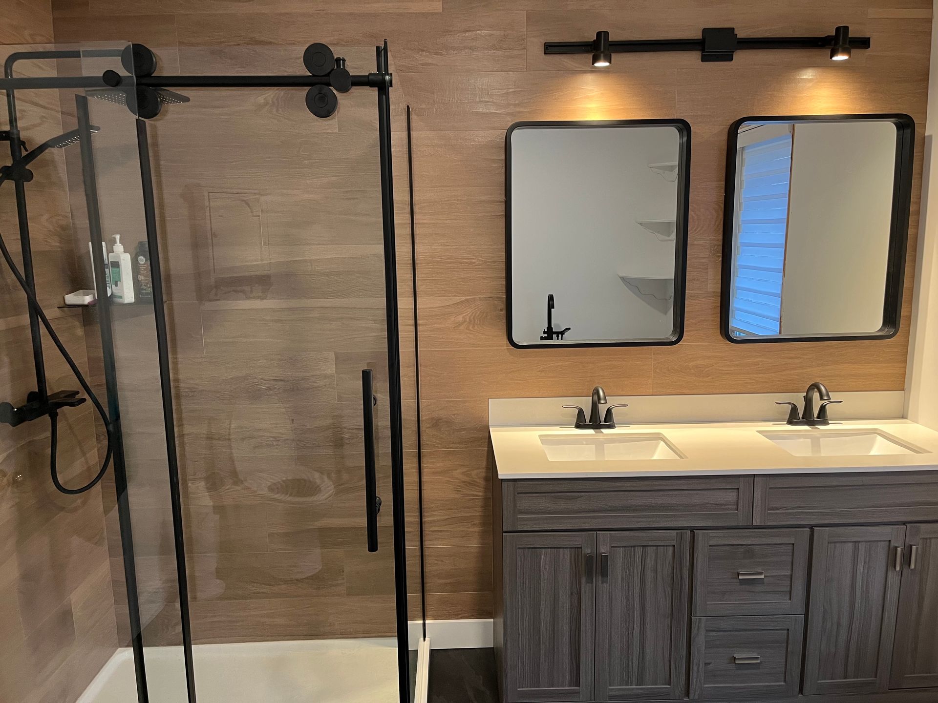Une salle de bain avec deux lavabos, une douche et deux miroirs.