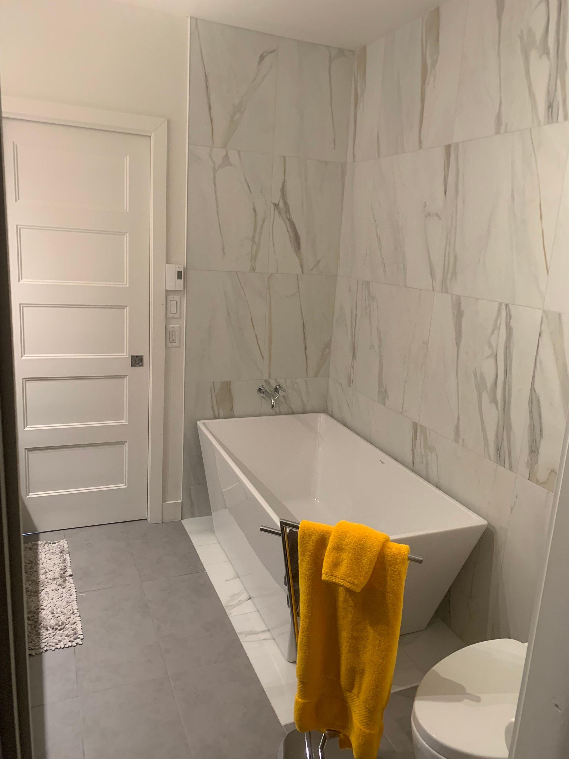 Une salle de bain avec une baignoire, des toilettes et une serviette jaune accrochée au mur.