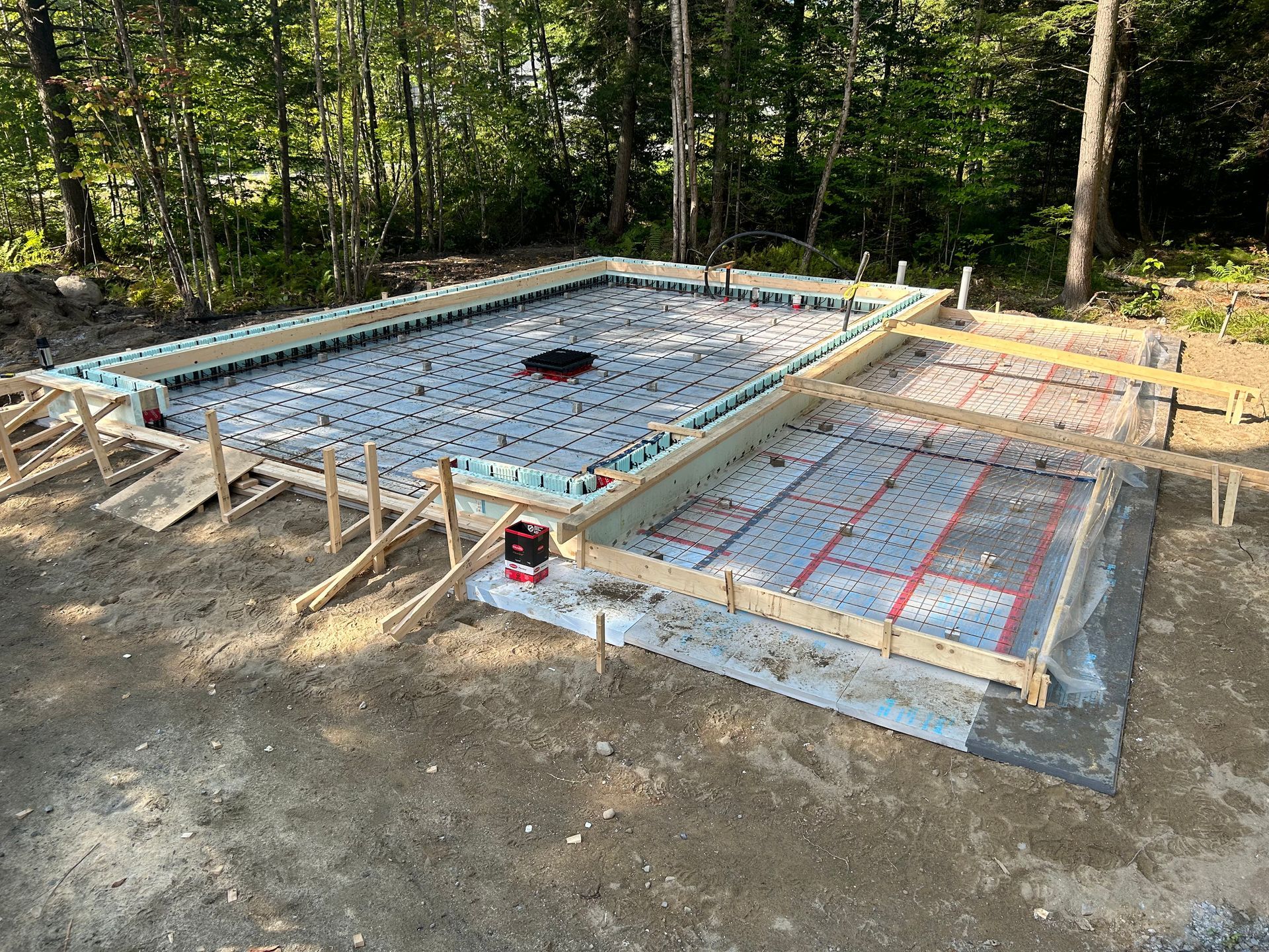 Une base en béton pour une maison est en cours de construction dans les bois.
