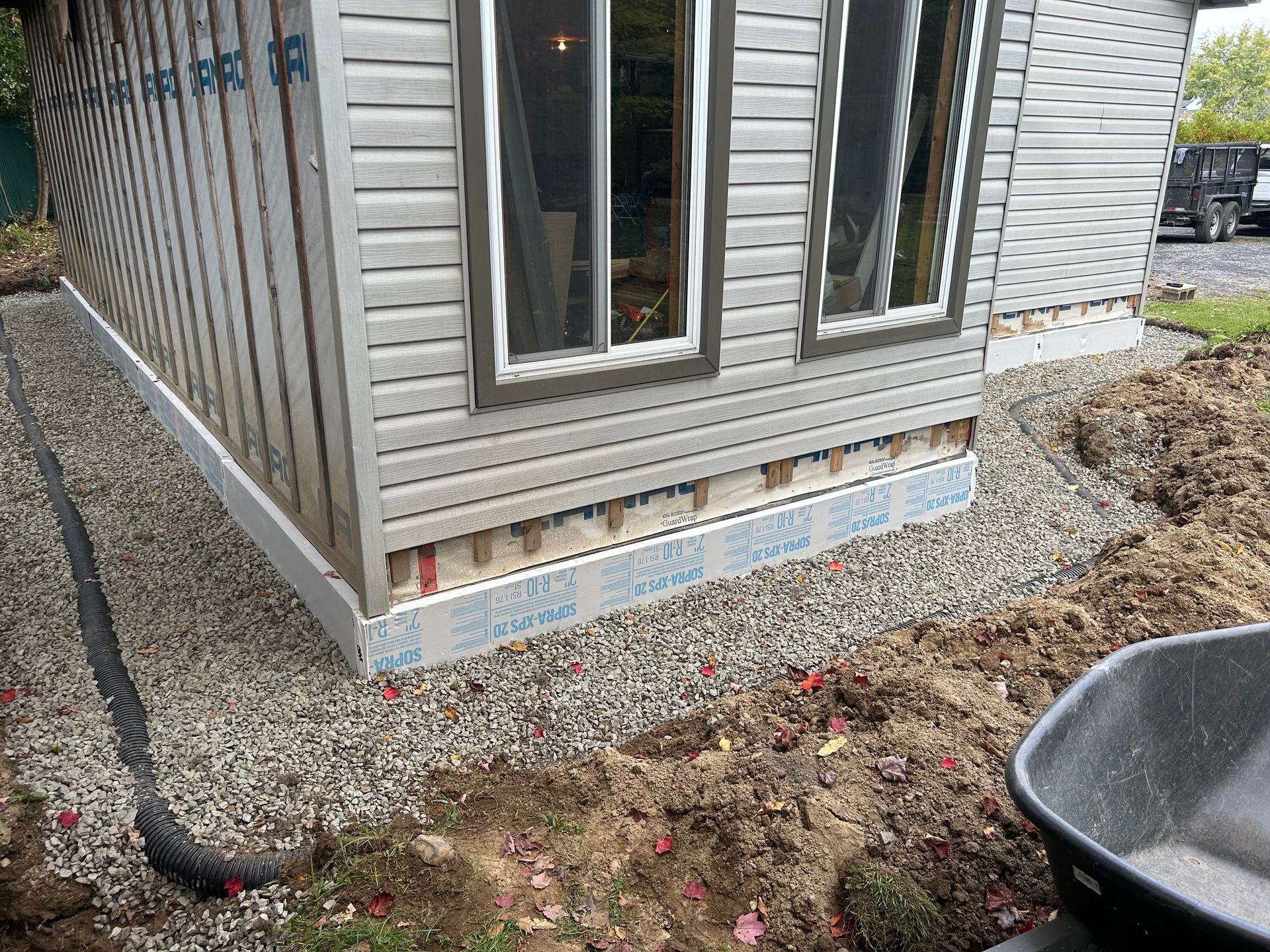 Une maison avec une brouette devant est en construction.