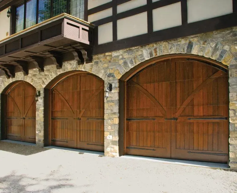 Stone building facade with three large wooden arched garage doors and a small balcony above Stone building facade with three large wooden arched garage doors and a small balcony above