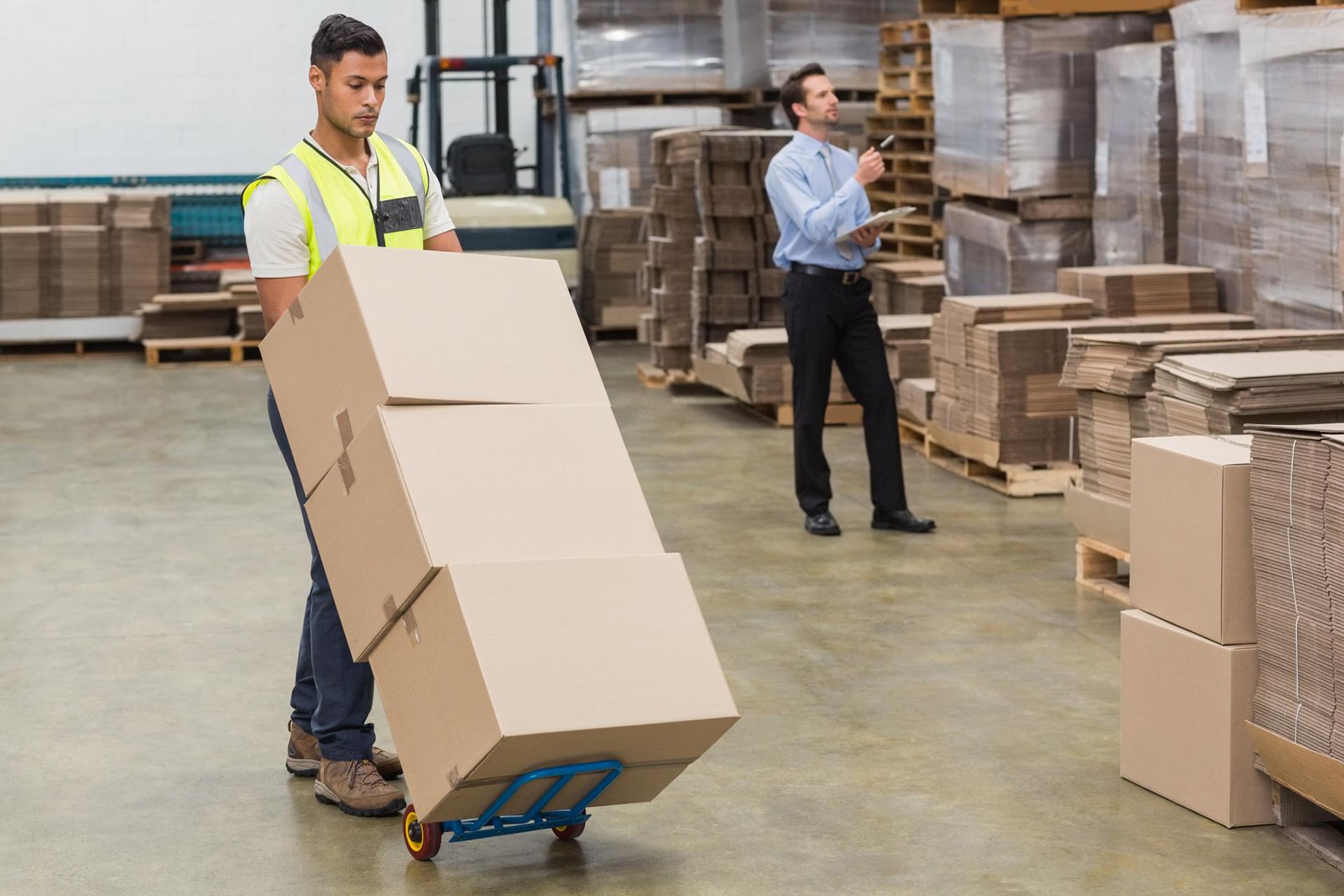 a man pushing a cart with boxes on it in a warehouse