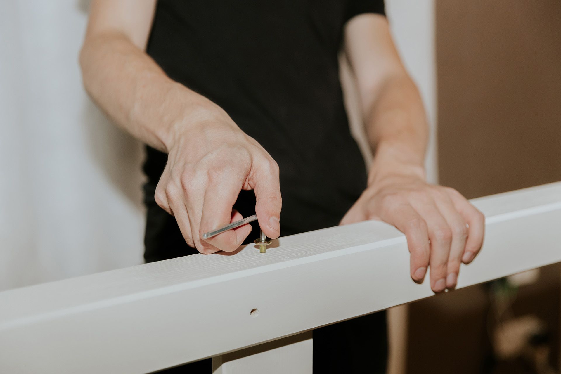 a man dissamebling furniture by unscrewing a nail from wooden frame