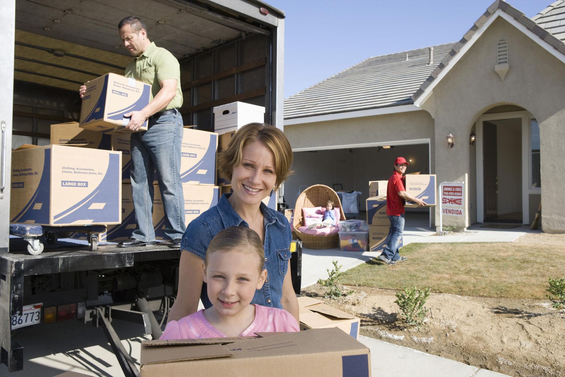 a family is standing in front of a moving truck holding boxes