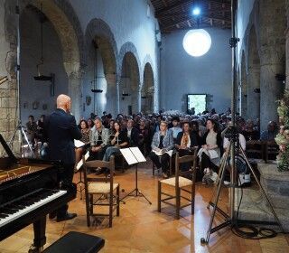 Un uomo sta suonando il pianoforte di fronte a una grande folla di persone in una chiesa.