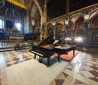 C'è un pianoforte al centro di una grande stanza in una chiesa.