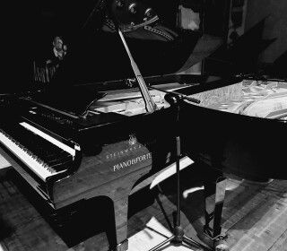 Una foto in bianco e nero di un pianoforte in una stanza buia.