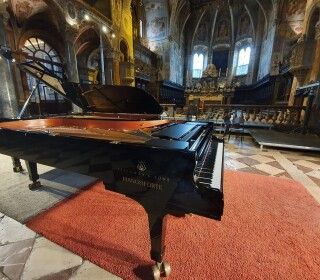 Un pianoforte è appoggiato su un tappeto rosso in una chiesa.