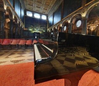 Un pianoforte è posizionato al centro di una grande stanza.