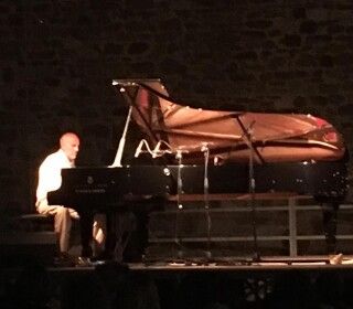 Un uomo suona il pianoforte su un palco di notte.