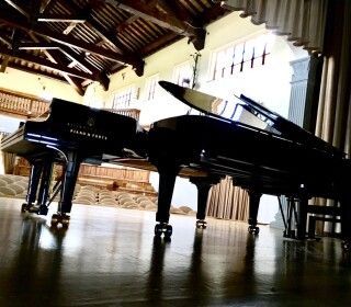 Due pianoforti sono appoggiati su un pavimento di legno in una stanza.