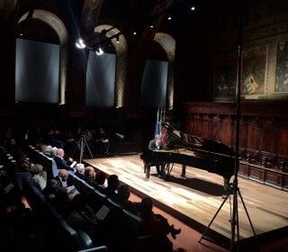 Un uomo sta suonando il pianoforte su un palco di fronte a una folla.