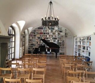 Una grande stanza con file di sedie e un pianoforte.