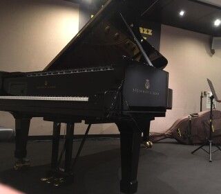 Un pianoforte a coda nero è posizionato in una stanza buia.