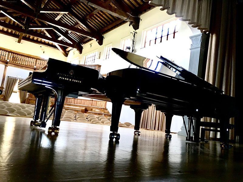 Un pianoforte è appoggiato su un pavimento di legno in una stanza.