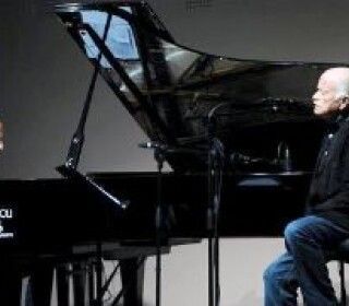 Un uomo è seduto davanti a un pianoforte e canta in un microfono.