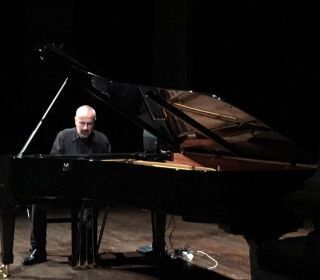 Un uomo sta suonando il pianoforte in una stanza buia.