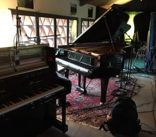 Un pianoforte è posizionato in una stanza accanto a una tastiera.