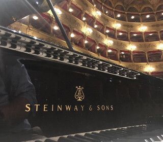 Un pianoforte a coda Steinway & Sons è posizionato di fronte a un grande auditorium.