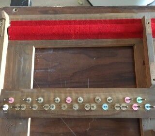 Una cornice di legno con dei bottoni è appoggiata su un tavolo di legno.