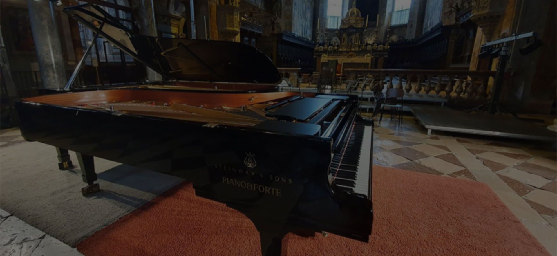 Un pianoforte a coda nero è appoggiato su un tappeto rosso in una chiesa.